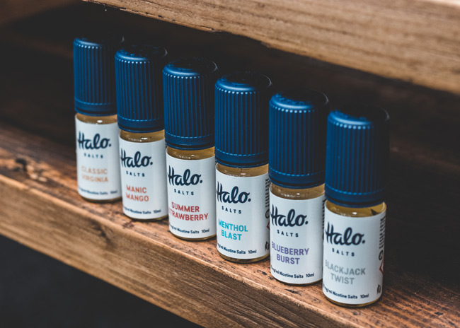 Halo nicotine salts e-liquids in a row on a wooden shelf.