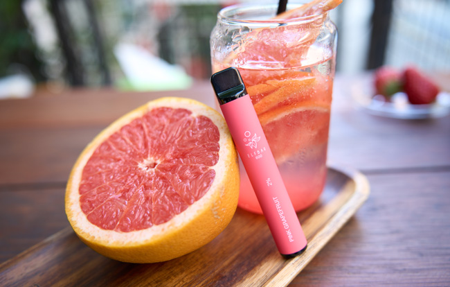 Elf Bar Pink Grapefruit disposable vape next to a pink drink and grapefruit.