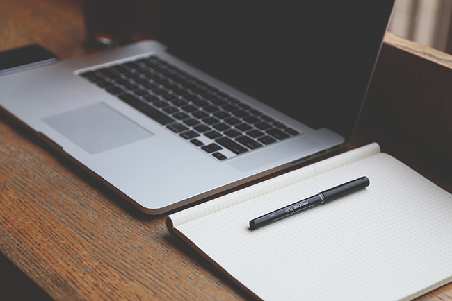 Mac book and pad of paper on a desk